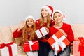 family  a young mother and her little daughter and son  wearing santa claus hats  celebrate the New Year at home while sitting on Royalty Free Stock Photo