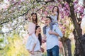 Young parents with small daugthers standing outside in spring nature.