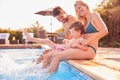 Family With Young Son Sitting On Edge Of Pool Having Fun On Summer Vacation In Outdoor Swimming Pool Royalty Free Stock Photo