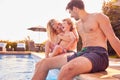 Family With Young Son Sitting On Edge Of Pool Having Fun On Summer Vacation In Outdoor Swimming Pool Royalty Free Stock Photo