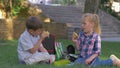 Famished schoolkids eat sandwiches during lunch time sitting on lawn in schoolyard