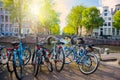 Famous Amsterdam view - parked bicycles next to the canal, view of the traditional bridge and houses. A beautiful sunny day. Royalty Free Stock Photo
