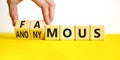 Famous or anonymous symbol. Concept word Famous and Anonymous on wooden cubes. Businessman hand. Beautiful yellow table white Royalty Free Stock Photo