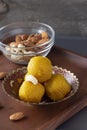 Famous authentic Indian sweets Laddu made from besan or chickpeas flour. Vegetarian and healthy food. Wooden plate background.