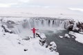 Famous and beautiful Icelandic waterfall Godafoss north iceland.Tourist photographer in red jacket standing at Godafoss powerful