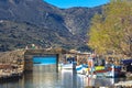 The famous canal of Elounda with the ruins of the old bridge, fishing boats and a group of young winter swimmers, Crete, Greece. Royalty Free Stock Photo