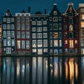 Famous dancing houses and buildings in Amsterdam with reflection in canal water at night, beautiful European landscape Royalty Free Stock Photo