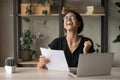 Excited young lady celebrate business success holding paper financial report