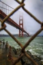 The famous Golden Gate bridge viewed through a rusty chain link fence on a cloudy day in San Francisco, California Royalty Free Stock Photo