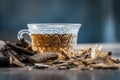 Famous herb Licorice root or Liquorice root or Mulethi root on wooden surface along with its beneficial tea in a transparent cup.