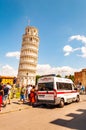 The famous leaning Tower of Pisa or La Torre di Pisa at the Cathedral Square, Piazza del Duomo full of tourists and ambulance on Royalty Free Stock Photo