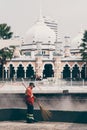 Famous Masjid Jamek mosque in Kuala Lumpur and old janitor cleaning the street