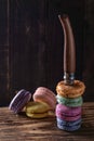 A famous model of a French knife sticks out of cookies on a dark wooden background. Multi-colored macaroons on the table top made