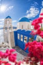 Oia village with churches against red flowers on Santorini island in Greece Royalty Free Stock Photo