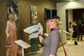 Famous people in the art gallery. Vintage exhibition of women`s clothing and hats. The exhibition has many journalists who take pi