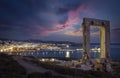 The famous Portara marble gate in front of the illuminated town of Naxos island