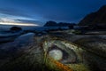 Famous rock formation called Dragon\'s Eye captured during dusk. Lamp lit stone in the natural pool at the Uttakleiv Beach. Royalty Free Stock Photo