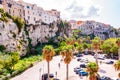 Famous sea promenade in Tropea with high cliffs with built on top city buildings and apartments. Parking area on the street.