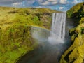 Famous Skogafoss waterfall with a rainbow. Dramatic Scenery of Iceland during sunset.