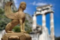 The famous Sphinx of Naxos preserved in the Archaeological Museum of Delphi against the backdrop of the Temple of Athena