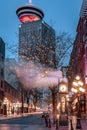 The famous Steam Clock in Gastown with Vancouver Lookout building at night Royalty Free Stock Photo