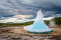 Famous Strokkur fountain geyser hot blue water eruption with cloud sky and surrounding Icelandic landscape, Iceland Royalty Free Stock Photo