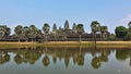 The famous temple of Angkor Wat. In the foreground is a lake, in the distance, against a clear blue sky, the ruins