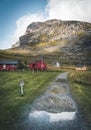 Famous tourist attraction of Reine in Lofoten, Norway with red rorbu houses, clouds, rainy day with bridge and grass and Royalty Free Stock Photo