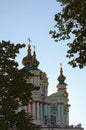 Famous touristic place and romantic travel destination in Kyiv. Saint Andrew Church hides behind the green foliage