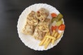 Arabic chicken shawarma plate with fried fries and pickled vegetables on dark wooden background, top view. Shawarma wrap on white