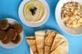 Tahini sauce, pita bread, rice with vermicelli, falafel and molokhia soup on blue background. Flat lay, top view. Egyptian food