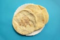 Famous traditional Arabic pita bread in white plate on blue background Royalty Free Stock Photo