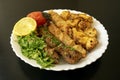 Grilled chicken shashlik, lamb, beef kofta kebab, vegetables, lemon on white plate on dark wooden background Royalty Free Stock Photo
