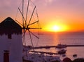 Famous traditional Greek windmill, Mykonos, Greece against sunset and sea. Beautiful sky, sun touch sea horizon Royalty Free Stock Photo