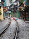 famous train street in Hanoi and man cleaning with buckets on the tracks, Vietnam
