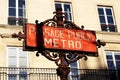 Paris Metro sign with parisian facade in background France