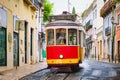 Famous vintage yellow tram in the narrow streets of Alfama district in Lisbon, Portugal