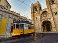 A famous yellow tram 28 passing in front of Santa Maria cathedral in Lisbon, Portugal at dusk or twilight