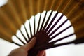 Fan in Chinese style in a female hand close-up on a white shiny background Royalty Free Stock Photo