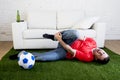 Fanatic football fan on green grass carpet emulating soccer stadium pitch mocking player in pain hurt on ankle Royalty Free Stock Photo