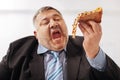 Fanatical obese man biting a slice of pizza