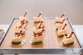 Fancy beautiful mini cakes on wooden plate on even snack table Royalty Free Stock Photo