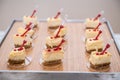 Fancy beautiful mini cakes on wooden plate on even snack table. Royalty Free Stock Photo