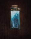 Fancy bottle with blue bath salts for relaxing spa treatments with wooden background Royalty Free Stock Photo