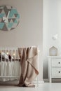 Fancy clack on the wall of elegant baby bedroom interior with white wooden crib with pastel pink blanket and cotton ball lights Royalty Free Stock Photo
