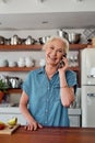 Fancy coming over for breakfast. a mature woman using a smartphone while preparing a healthy breakfast in the kitchen at Royalty Free Stock Photo