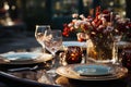 A fancy dinner table, wine glasses, a candle, white and red flowers in a see through vase on a black surface, a dark blurred Royalty Free Stock Photo