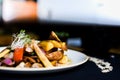 Fancy dish with baby corns sliced onions, carrots, and roasted potatoes on a white plate