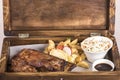 Fancy dish with grilled pork ribs, barbecue sauce, French fries, Coleslaw salad, in a wooden box Royalty Free Stock Photo