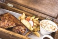 Fancy dish with grilled pork ribs, barbecue sauce, French fries, Coleslaw salad, in a wooden box Royalty Free Stock Photo